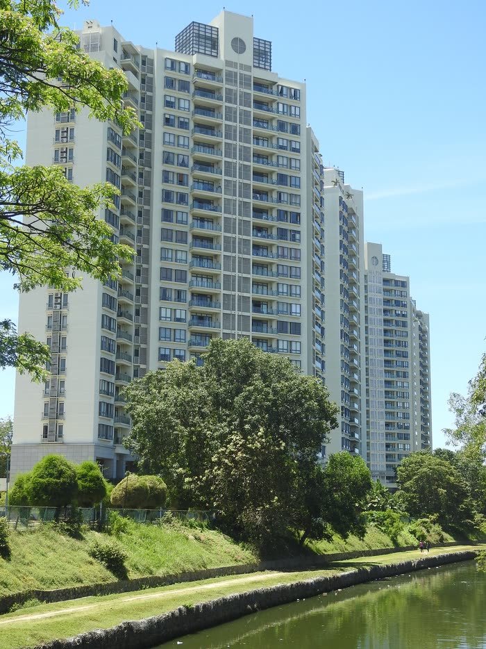 A white residential tower at Havelock City, Colombo, behind trees and a canal.