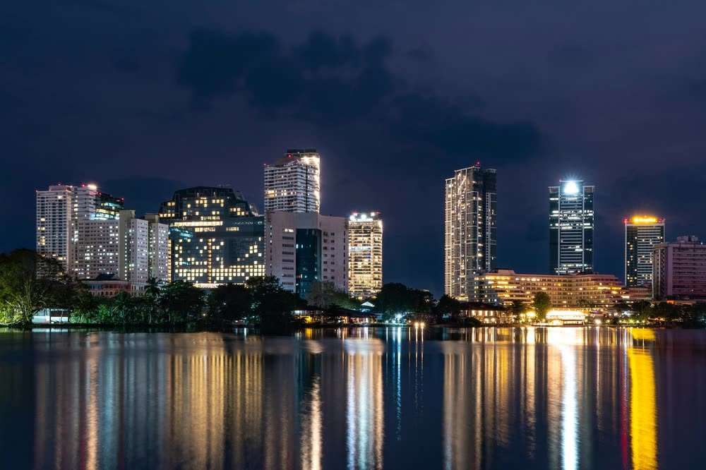 The Colombo skyline at night, reflected in still water.
